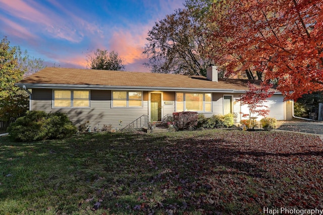 ranch-style house featuring a garage and a yard