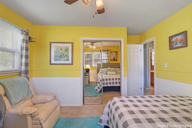 carpeted bedroom with ceiling fan and a closet