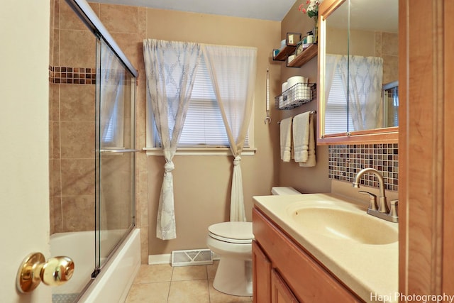 full bathroom with tile patterned flooring, shower / bath combination with glass door, toilet, backsplash, and vanity