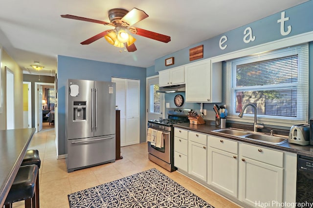 kitchen with stainless steel appliances, ceiling fan, sink, white cabinetry, and light tile patterned flooring