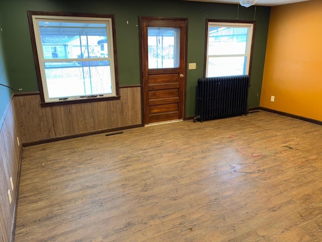 entrance foyer with wood walls, light hardwood / wood-style flooring, and radiator heating unit