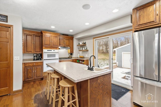 kitchen featuring hardwood / wood-style flooring, sink, a center island with sink, and stainless steel fridge