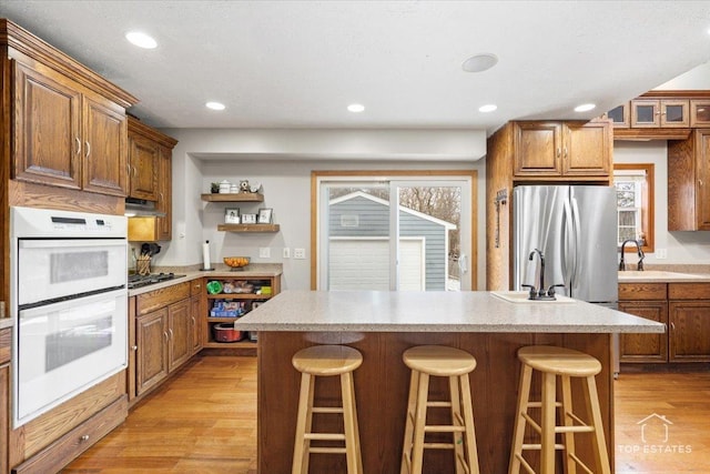 kitchen with stainless steel appliances, a kitchen breakfast bar, light hardwood / wood-style floors, and a kitchen island