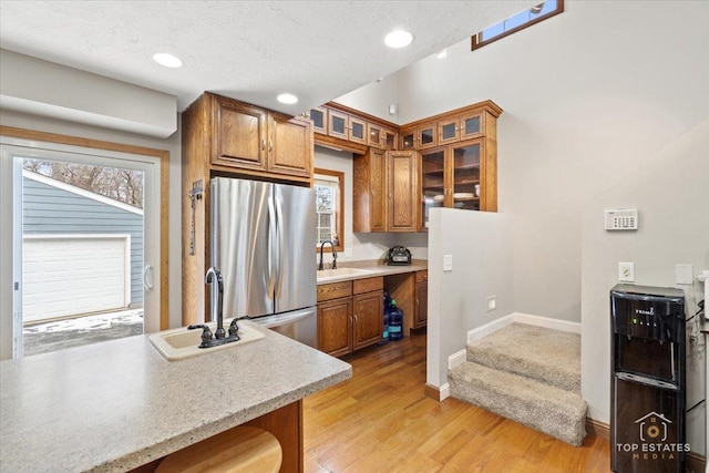 kitchen featuring stainless steel refrigerator, built in desk, sink, and light hardwood / wood-style flooring