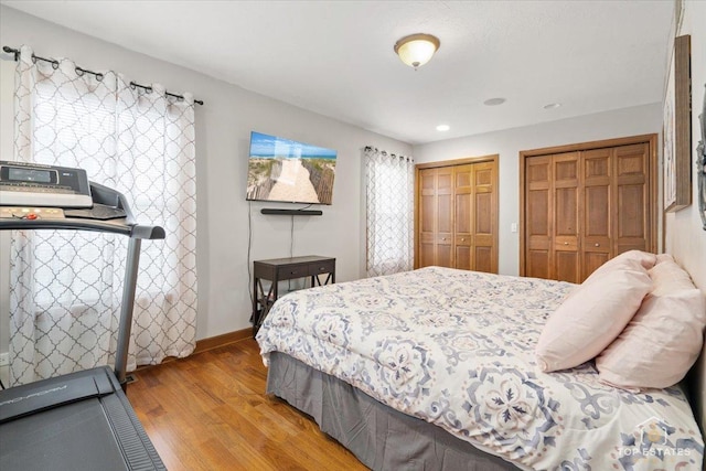 bedroom with two closets and light hardwood / wood-style floors