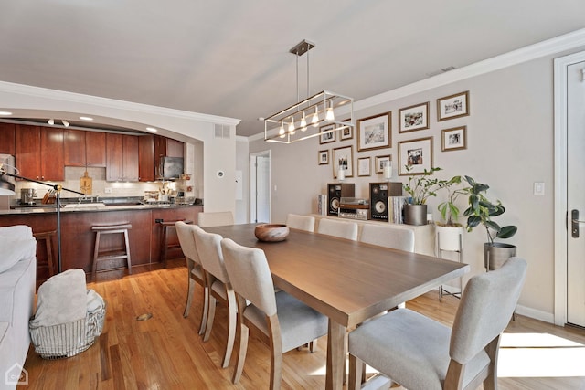 dining area with light wood-type flooring and ornamental molding