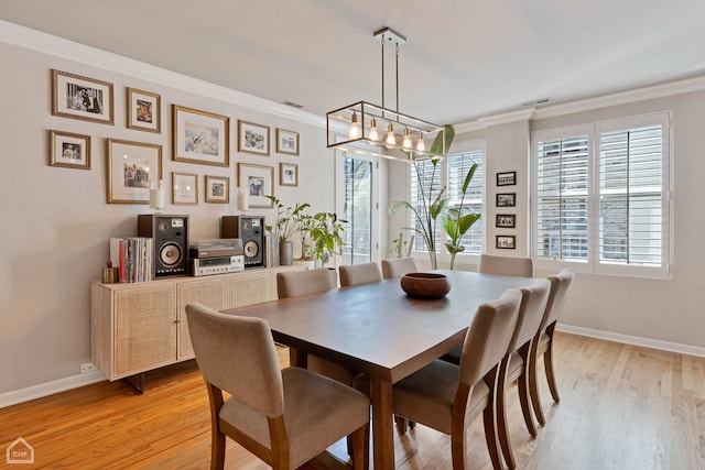 dining room featuring light hardwood / wood-style flooring, crown molding, and a chandelier