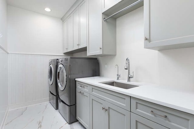 washroom featuring cabinets, washing machine and clothes dryer, and sink