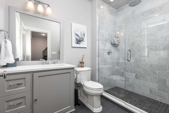 bathroom with tile patterned floors, vanity, toilet, and a shower with shower door