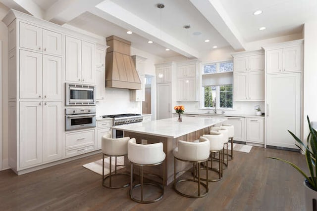 kitchen with appliances with stainless steel finishes, white cabinetry, a kitchen breakfast bar, a kitchen island, and decorative light fixtures