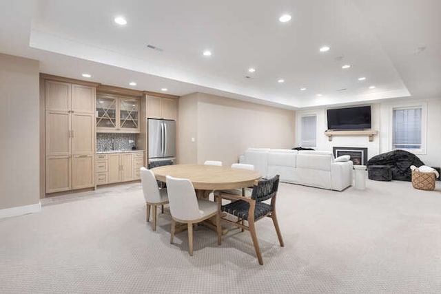 dining area featuring light carpet, a tray ceiling, and indoor bar