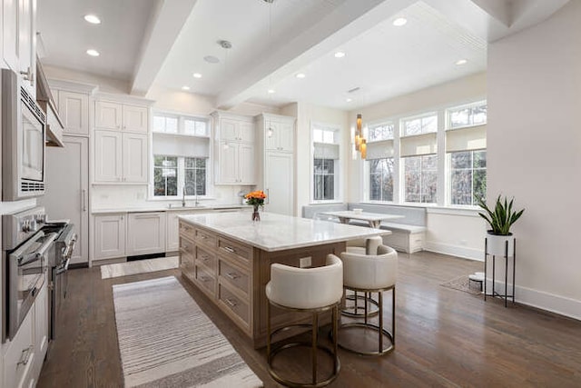 kitchen with white cabinetry, stainless steel microwave, and a large island