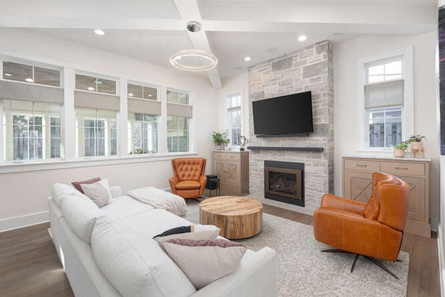 living room featuring hardwood / wood-style flooring, coffered ceiling, a stone fireplace, and beam ceiling