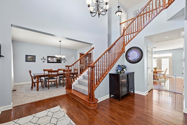 stairway with a high ceiling, hardwood / wood-style floors, and an inviting chandelier