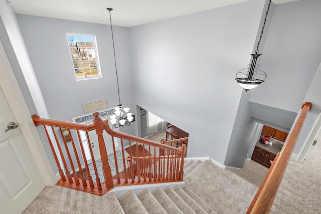 stairs with a chandelier, a towering ceiling, and carpet floors