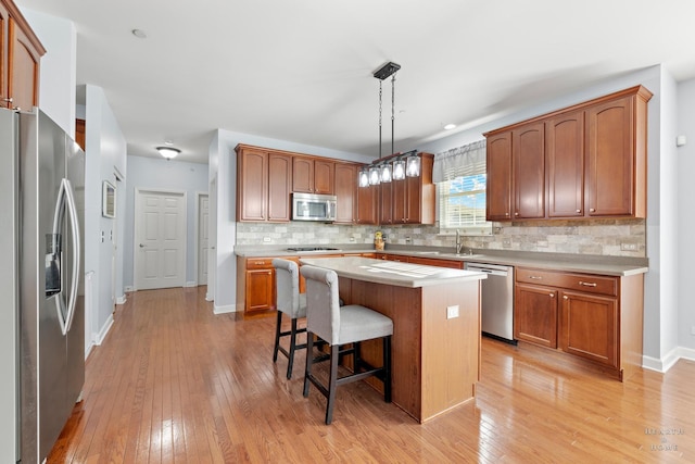 kitchen with backsplash, a center island, hanging light fixtures, a breakfast bar area, and stainless steel appliances