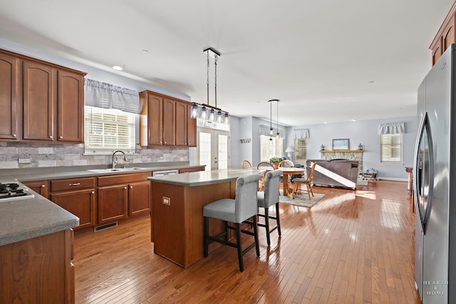 kitchen featuring a kitchen island, decorative light fixtures, stainless steel appliances, sink, and a breakfast bar area