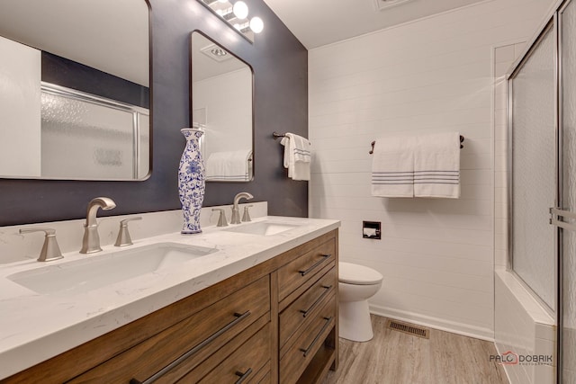 bathroom with toilet, vanity, a shower with door, and hardwood / wood-style floors