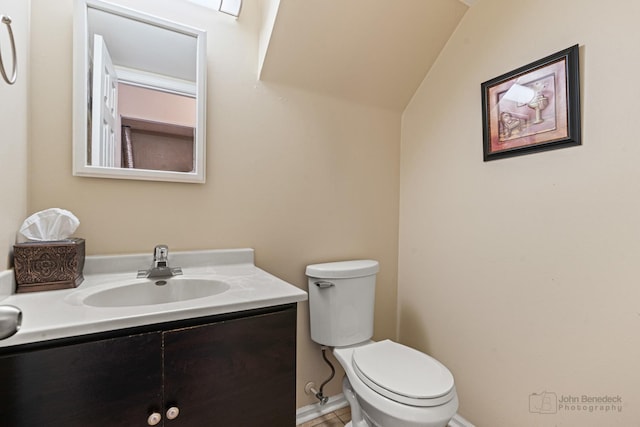 bathroom featuring toilet, vaulted ceiling, and vanity