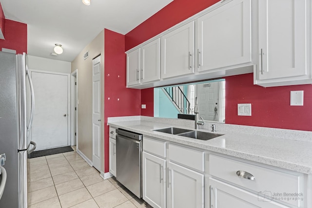 kitchen with light stone countertops, white cabinetry, stainless steel appliances, sink, and light tile patterned floors