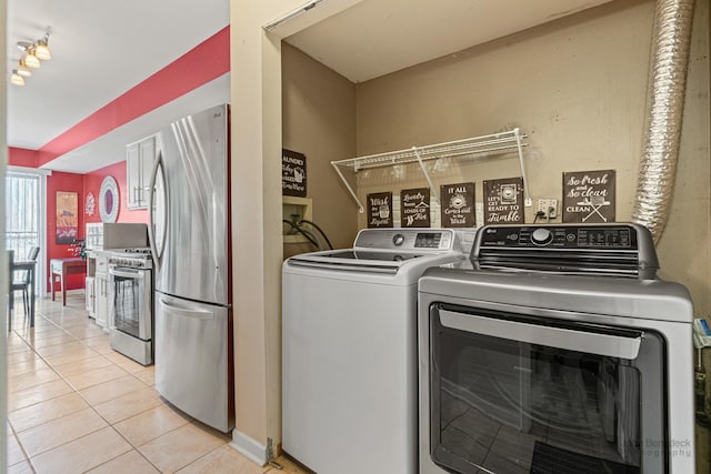 washroom featuring washing machine and dryer and light tile patterned floors