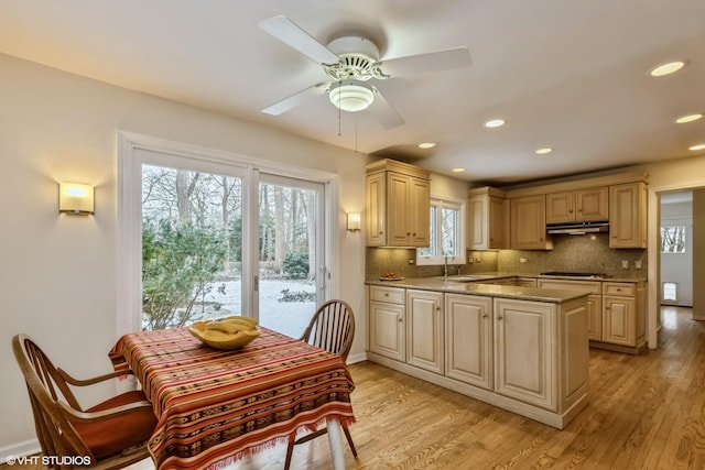 kitchen featuring sink, ceiling fan, backsplash, light stone countertops, and light wood-type flooring