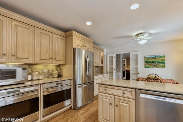 kitchen with light brown cabinetry, tasteful backsplash, light wood-type flooring, ceiling fan, and stainless steel appliances