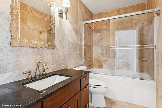 full bathroom featuring toilet, decorative backsplash, tile walls, enclosed tub / shower combo, and vanity