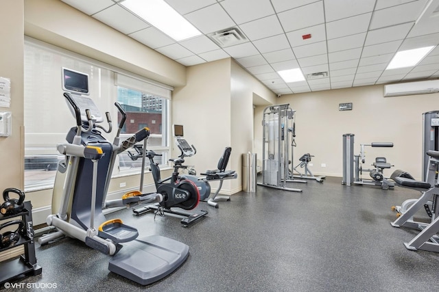 exercise room with a drop ceiling and a wall mounted AC