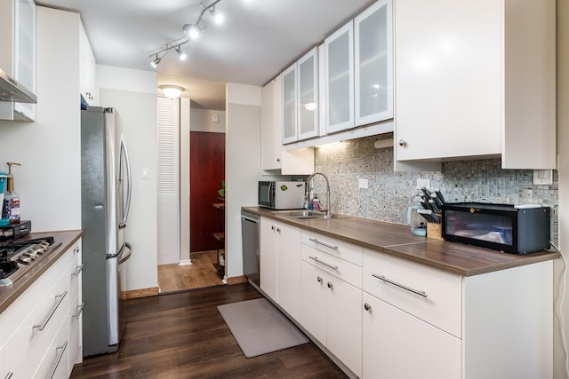 kitchen featuring appliances with stainless steel finishes, dark hardwood / wood-style floors, wall chimney exhaust hood, white cabinets, and sink