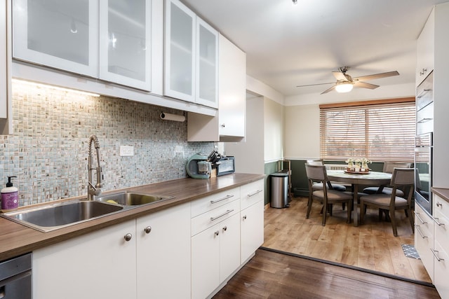 kitchen featuring stainless steel appliances, dark hardwood / wood-style floors, backsplash, white cabinets, and sink