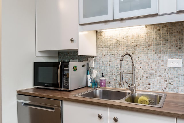 kitchen featuring sink, white cabinetry, dishwasher, and tasteful backsplash