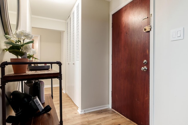 corridor with ornamental molding and light hardwood / wood-style floors