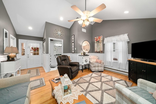 living room featuring a wealth of natural light, lofted ceiling, light hardwood / wood-style floors, and a baseboard radiator