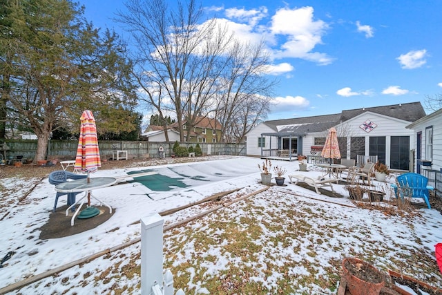 yard layered in snow with a patio area and a covered pool