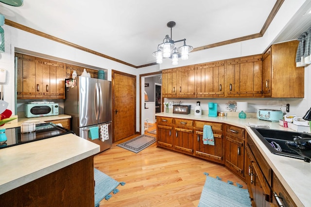 kitchen with crown molding, pendant lighting, light hardwood / wood-style flooring, and stainless steel refrigerator