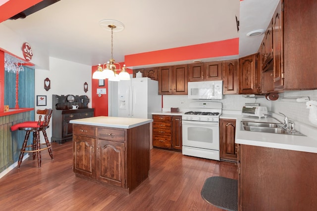 kitchen featuring white appliances, a center island, a notable chandelier, decorative backsplash, and sink