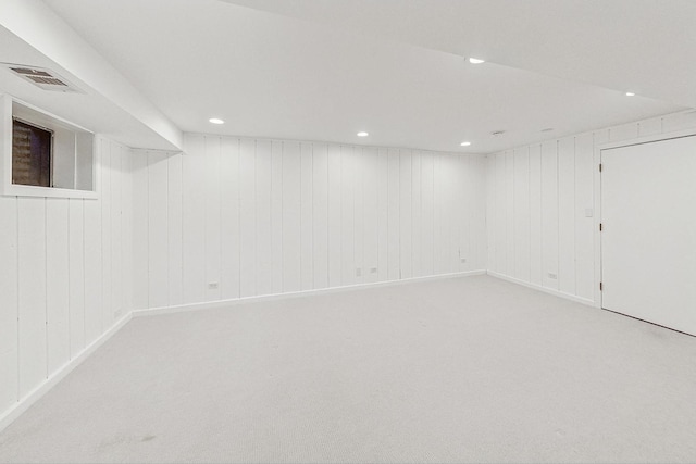 basement with wooden walls and light colored carpet