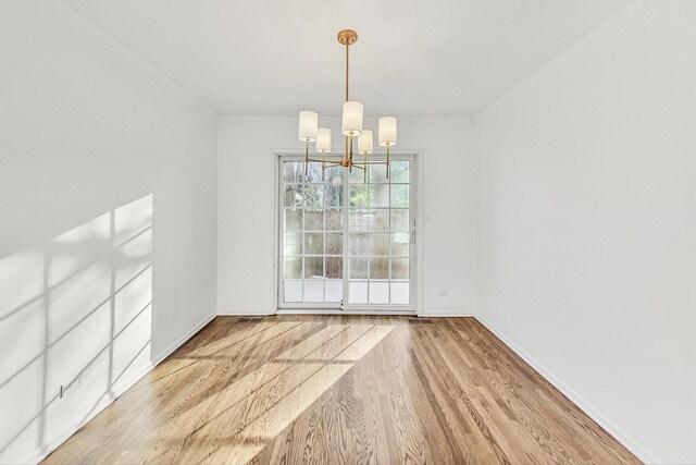 unfurnished dining area with a chandelier, hardwood / wood-style flooring, and ornamental molding