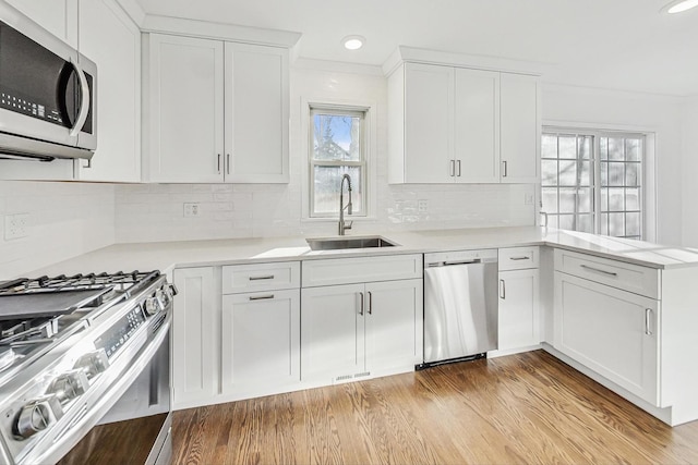 kitchen with white cabinets, stainless steel appliances, kitchen peninsula, sink, and backsplash