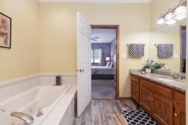 bathroom with hardwood / wood-style flooring, a relaxing tiled tub, and vanity