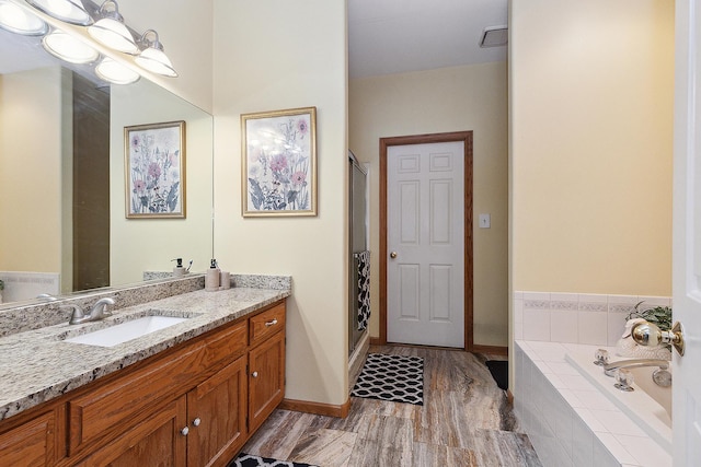 bathroom with hardwood / wood-style flooring, independent shower and bath, and vanity