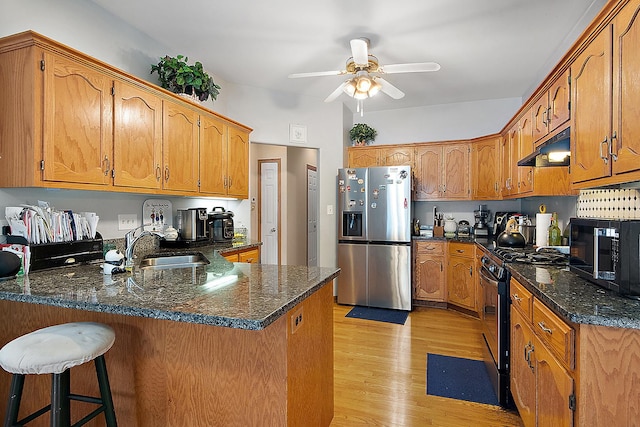 kitchen with kitchen peninsula, light hardwood / wood-style flooring, a breakfast bar, appliances with stainless steel finishes, and ceiling fan