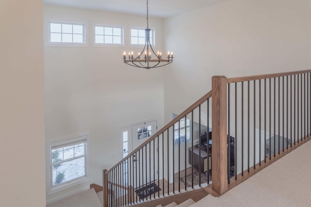 stairs featuring carpet, an inviting chandelier, and a healthy amount of sunlight