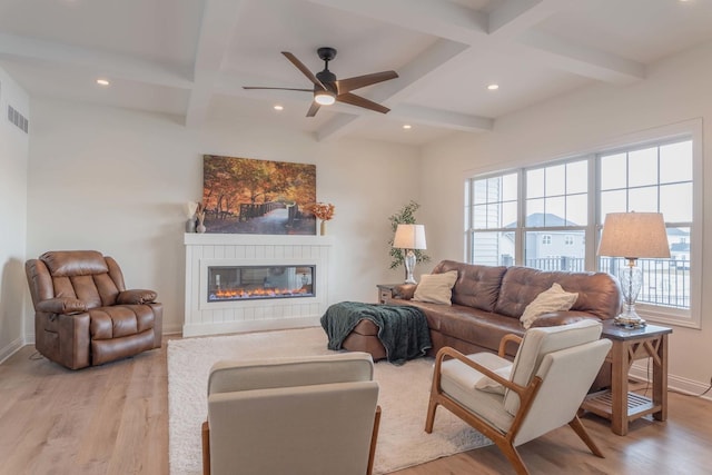 living room with a healthy amount of sunlight, light wood-type flooring, a fireplace, and beam ceiling