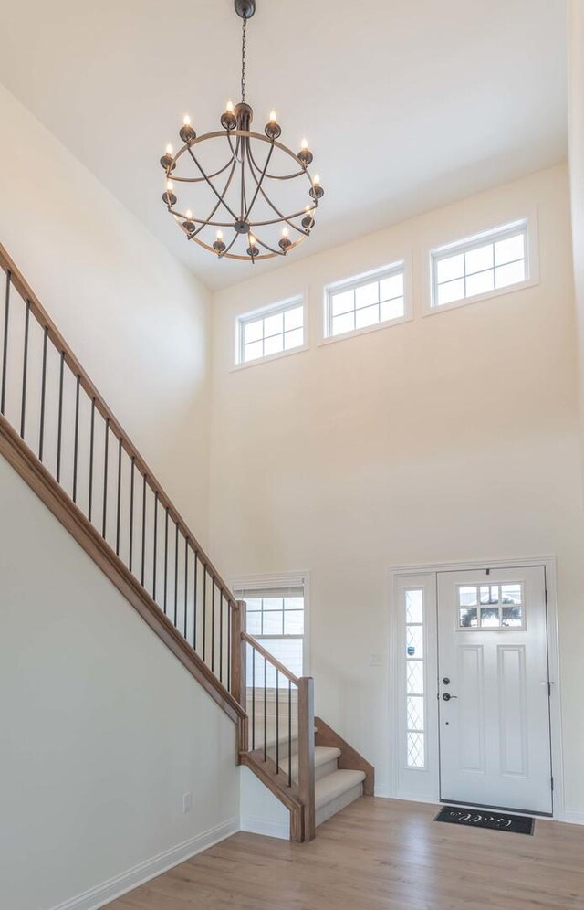 entrance foyer with a high ceiling, light hardwood / wood-style floors, and a chandelier