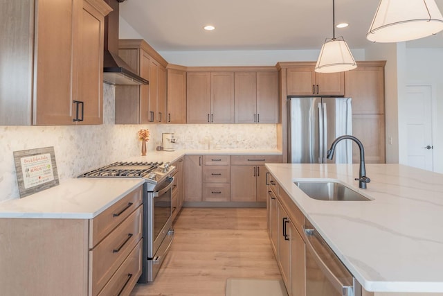 kitchen featuring appliances with stainless steel finishes, wall chimney exhaust hood, sink, decorative light fixtures, and tasteful backsplash