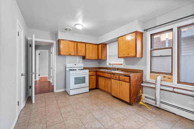 kitchen with sink, white range with gas stovetop, baseboard heating, and light tile patterned floors