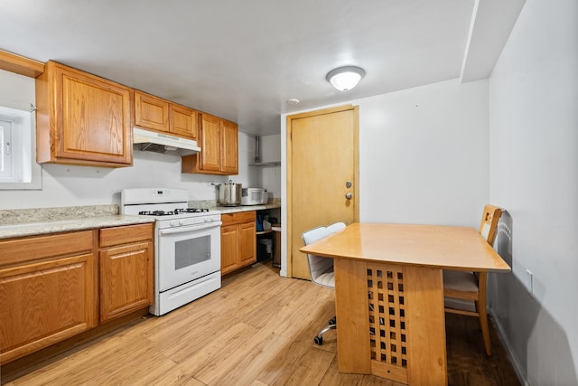 kitchen with light hardwood / wood-style floors, a kitchen bar, and white gas range oven