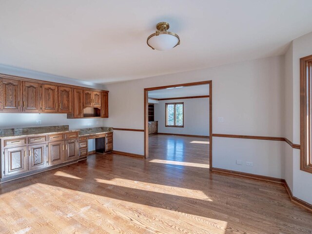 kitchen with hardwood / wood-style floors, stainless steel appliances, a kitchen island, light stone counters, and sink